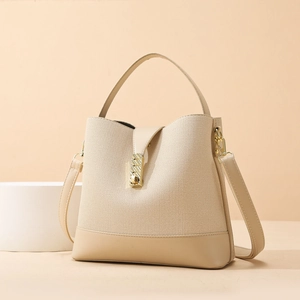 Minimalist beige woven bucket bag with gold buckle and adjustable shoulder strap