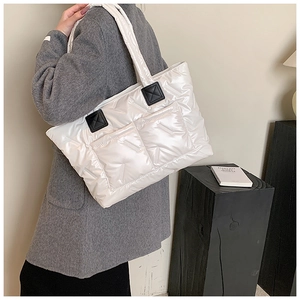 Detailed view of white quilted down tote bag with dual front pockets and glossy waterproof finish