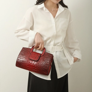Detail of burgundy crocodile-embossed tote bag held by model for commute fashion style