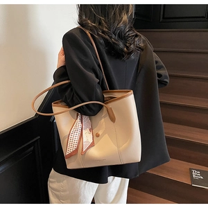 Large beige tote bag with brown leather trim and decorative scarf shown on model