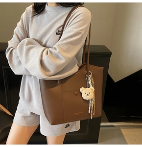 Detail of coffee tote bag with front pocket and cute white plush bear charm on strap