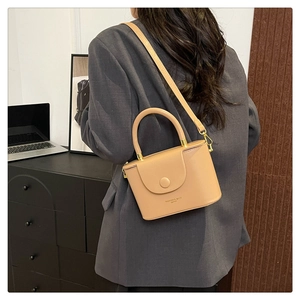Close-up of beige shoulder bag with leather texture and minimalist metal buckle