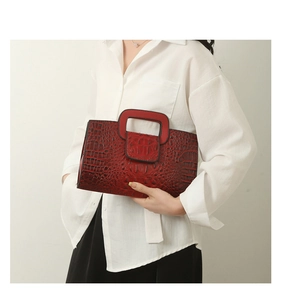 Close-up of red crocodile embossed pattern on a rectangular tote bag with handle cutout