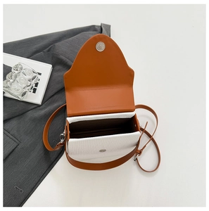 Top view of two-tone woven crossbody bag with orange flap and magnetic closure