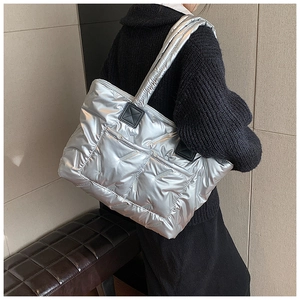 Detail of metallic silver quilted tote bag with V-shaped stitching and black leather accents