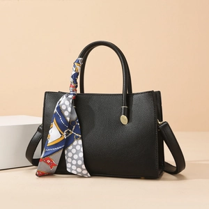 Détail d'un cabas noir en cuir grainé avec foulard décoratif sur la poignée