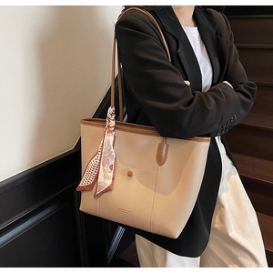Detail view of large apricot tote bag with brown trim, front snap pocket and silk scarf