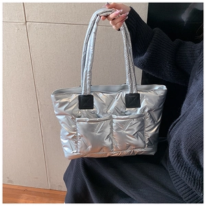 Detail of silver quilted puffer tote bag featuring oversized diamond stitching and front pockets