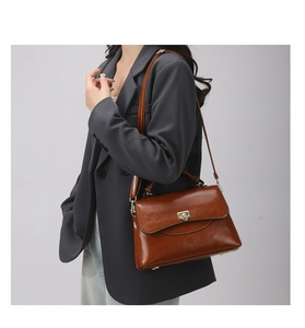 Detail of vintage dark brown faux leather handbag with golden metal lock and shoulder strap