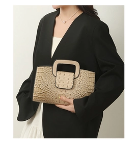 Detail of elegant crocodile embossed tote bag featuring square hollow top handle design