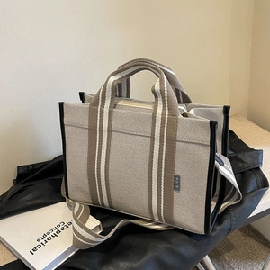 Beige canvas tote bag with striped handles and crossbody strap on fashion accessories