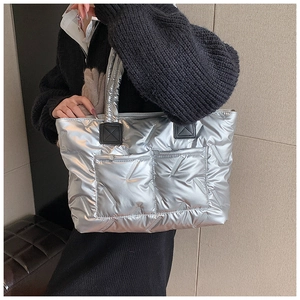 Detail of silver metallic quilted tote bag featuring large front pockets and black accents