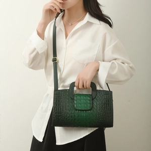 Detail of green crocodile-textured tote bag with adjustable shoulder strap on model
