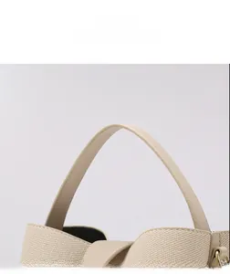 Detail view of beige woven fabric texture and premium leather handle with gold hardware