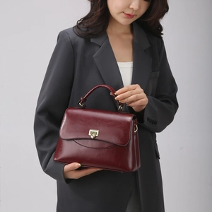 Fashionable dark red leather handbag for women featuring gold buckle and single handle