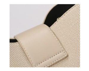 Detailed close-up of premium beige canvas and smooth leather stitching on a fashion tote bag