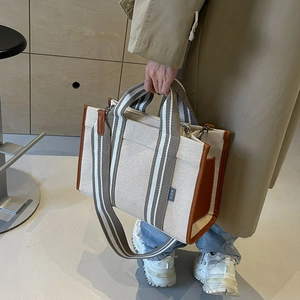 Versatile canvas tote bag with leather trim and striped strap for casual commuting