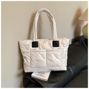 Close-up of white quilted tote bag featuring padded nylon texture and black leather handle detail