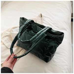 Detail of dark green quilted tote bag with glossy finish and soft down-filled texture