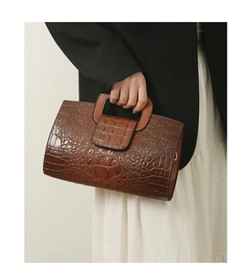 Detail of the brown crocodile pattern leather tote bag with a rigid top handle