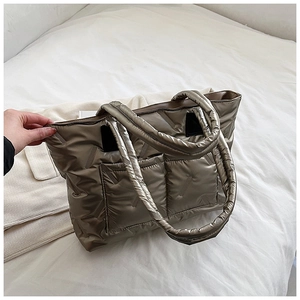Detail of a large quilted puffer tote bag with dual front pockets and metallic finish