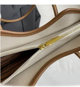 Detail of smooth gold zipper closure on creamy white textured tote with striped lining