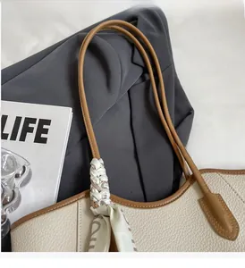 Close-up of beige lychee texture tote bag with brown handles and decorative silk scarf
