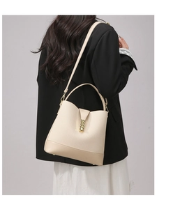Detail of beige bucket bag featuring woven texture and adjustable leather shoulder strap