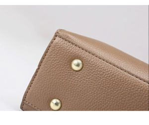 Vue macro du fond d'un sac en cuir litchi kaki avec rivets dorés de protection