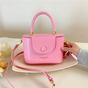Pink leather structured top handle bag with crossbody strap and golden fashion lettering
