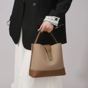 Detail of the two-tone bucket bag featuring canvas texture and golden metal buckle
