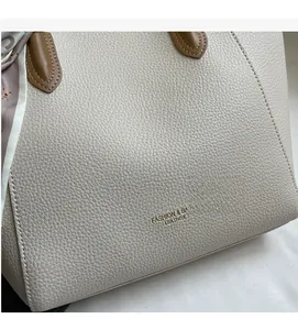 Close-up of beige lychee texture leather tote bag with geometric silk scarf detail