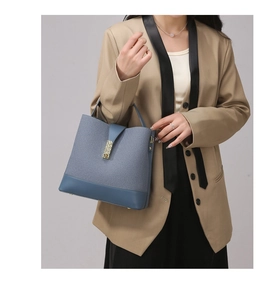 Detailed shot of a blue bucket bag featuring fabric stitching and a gold metal buckle