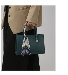 Détail d'un sac cabas vert foncé en cuir avec foulard élégant et finitions dorées