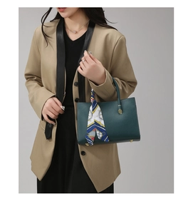 Détail du sac à main vert foncé en cuir grainé avec foulard en soie et finitions dorées