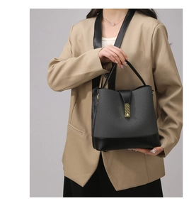Detail of grey fabric and black leather handbag with gold buckle and top handle
