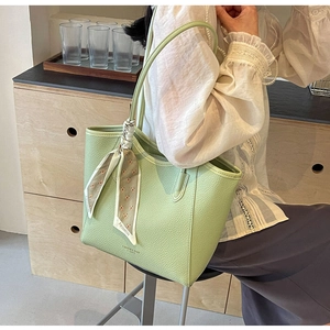Close-up of light green lychee leather tote bag with elegant floral scarf detail