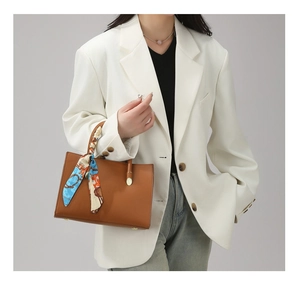 Détail du sac cabas en cuir marron avec foulard en soie et pieds de protection