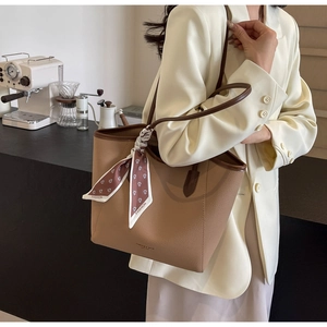 Detail of light brown lychee grain leather tote bag with floral scarf handle decoration