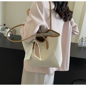 Detail of beige textured tote bag with brown edges and a stylish printed silk scarf
