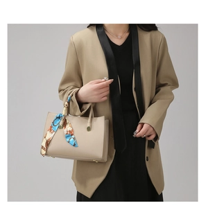 Détail du sac à main beige texturé avec poignée en foulard et pieds en métal