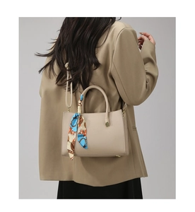 Détail du sac à main beige grainé avec un foulard en soie coloré sur la poignée