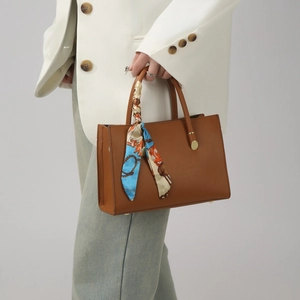 Détail du sac à main marron texturé avec foulard en soie floral élégant sur l'anse