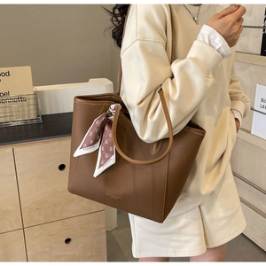 Detail of lychee pattern leather tote bag with printed silk scarf and gold logo
