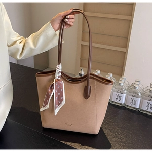 Detail of beige pebble leather tote bag with floral scarf and fashion logo on front
