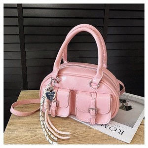 Détail d'un sac à main en cuir verni rose avec poches à rabat et breloque en cœur