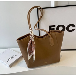 Detail of brown litchi pattern leather tote bag with silk scarf and gold lettering
