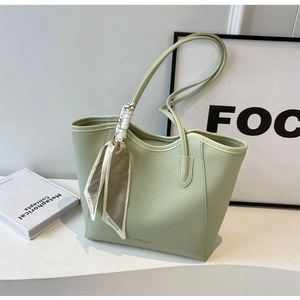 Close-up of mint green litchi leather tote bag with printed scarf on the handle