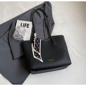 Close-up of black litchi grain leather tote bag featuring gold logo and printed silk scarf