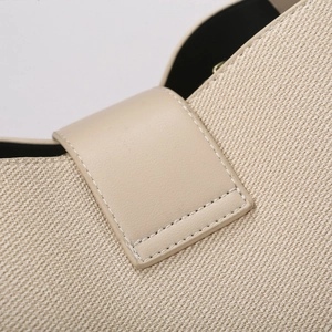 Close-up of beige woven bucket bag with detailed leather strap stitching and contrast texture